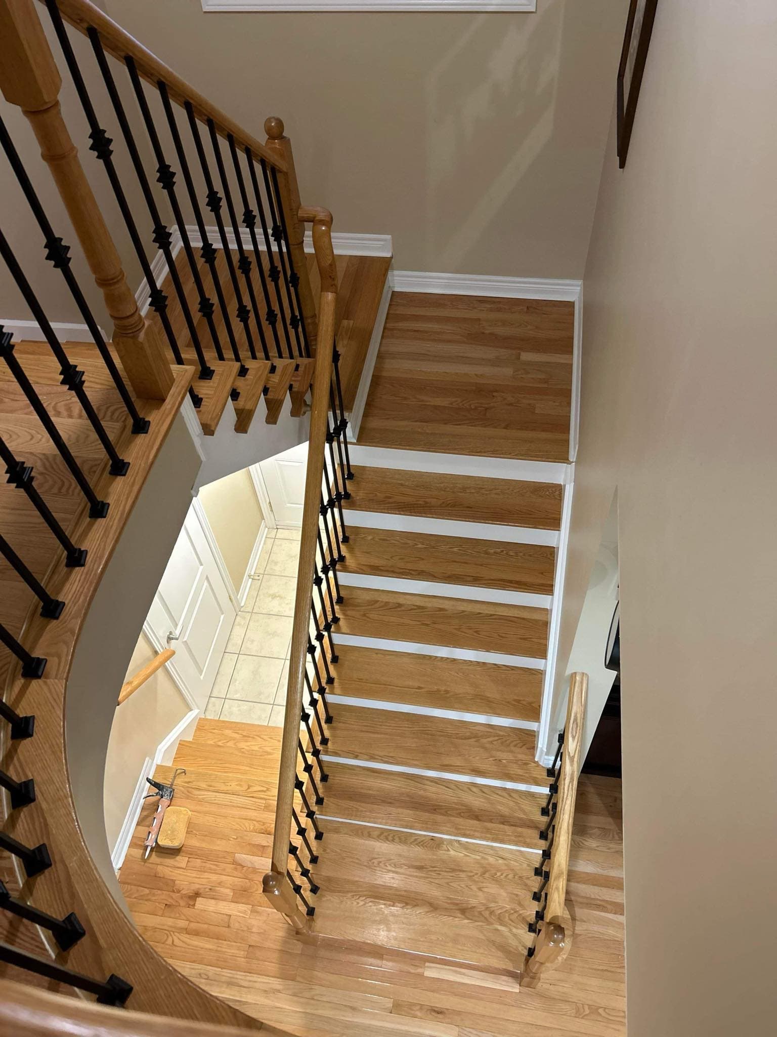 Light oak wooden staircase with white risers and black metal spindles viewed from above.
