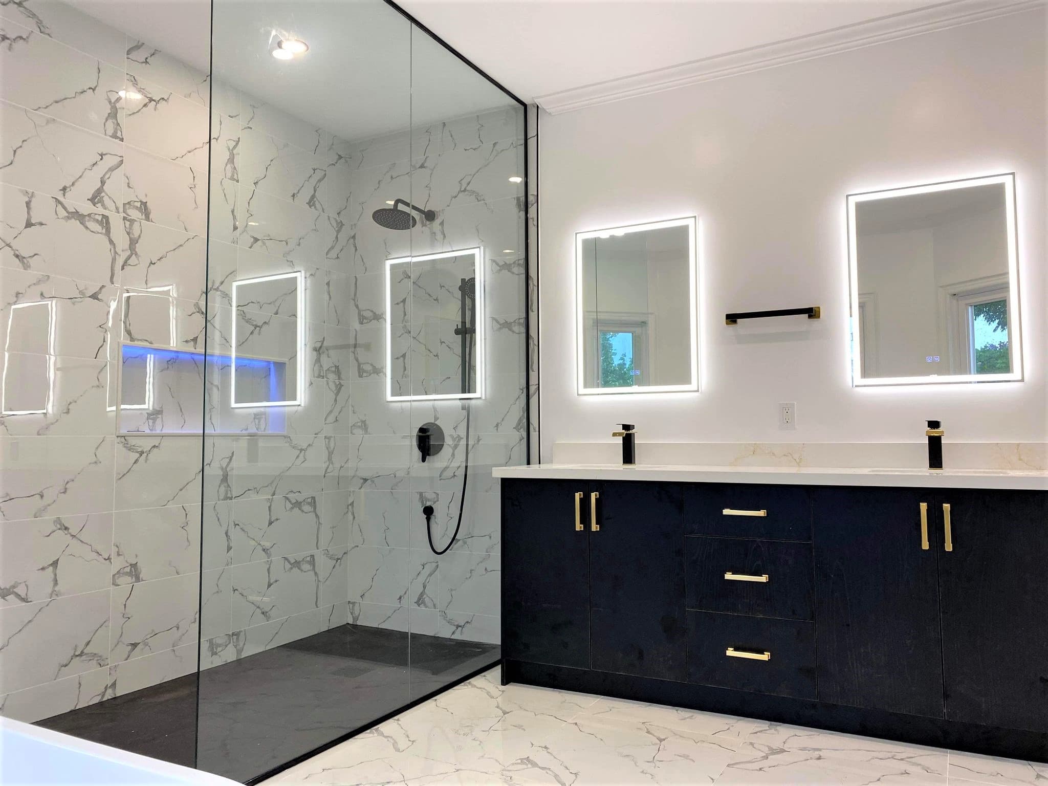 Modern bathroom with marble glass shower and dark double vanity featuring backlit mirrors.